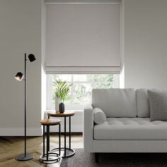 a white couch sitting next to a table with a lamp on it's side