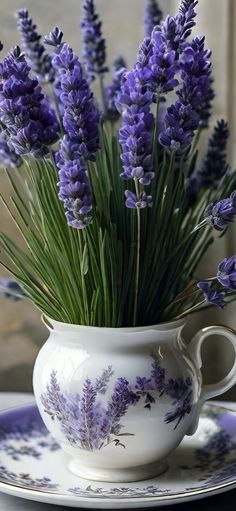 purple flowers are in a white vase on a plate