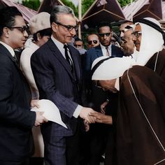 two men shaking hands in front of a group of people