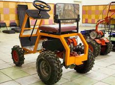 an orange and black four wheeled vehicle on tiled floor next to other vehicles in room