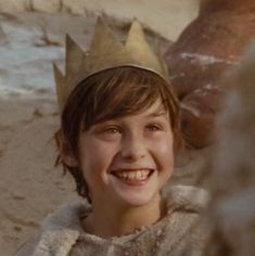 a young boy wearing a crown smiles at the camera