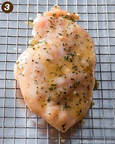 a piece of meat sitting on top of a wire rack with seasoning sprinkles