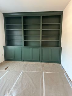 empty room with green bookcases in the middle and white walls, being prepared for remodel