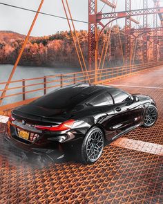 a black sports car driving across a bridge