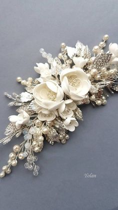 a bridal bouquet with white flowers and pearls on the side, sitting on a gray surface