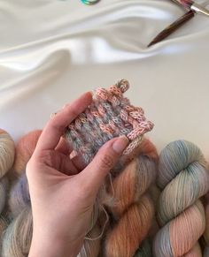 a person is knitting yarn on top of some skeins and crochet needles