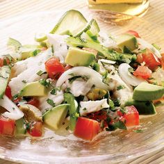 a salad with cucumbers, tomatoes and onions in a glass bowl on a table