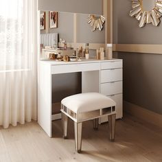 a white vanity with mirror and stool next to it on a wooden floor in front of a window