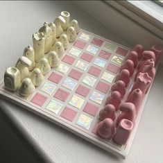 a pink and white checkerboard board with small elephant figurines on it