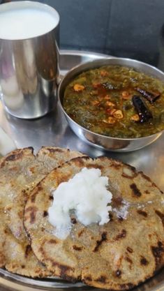 two flat breads on a metal tray next to a cup of milk