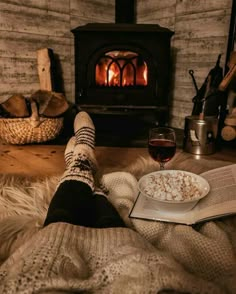 a person laying on the floor with their feet up next to an open book and a glass of wine