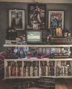 there is a book shelf with many movies on it and two framed pictures above the bookshelf