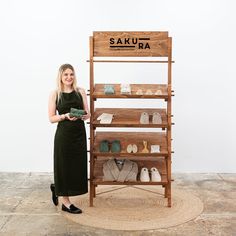 a woman standing in front of a wooden shoe rack with shoes on it and a sign that says sakura