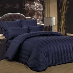 a bed with blue comforter and pillows in a room next to a night stand