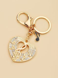 a heart shaped keychain with musical notes on the front and back sides, in gold tone