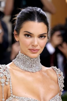 a woman in a silver dress with jewels on her neck