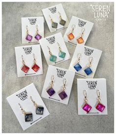 seven different colored glass earrings on display in front of a card with the words screen luma