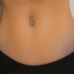 a woman's stomach with a necklace on top of her belly and an earring hanging from the back