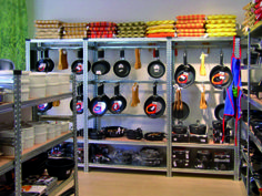 the shelves are full of pots and pans on racks, along with other items