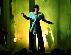 a woman standing in front of a green curtain