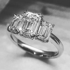 an emerald cut diamond ring with three baguets on the band and side stones