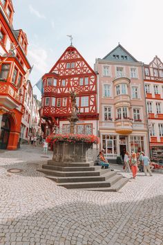 a red and white building with people walking around in front of it on a cobblestone street