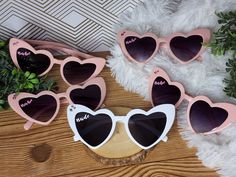 pink and white heart shaped sunglasses with the word bride written on them sitting on a wooden table