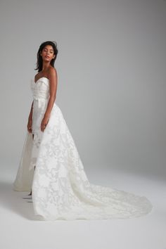 a woman in a white wedding dress posing for the camera with her hands on her hips