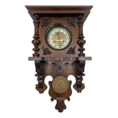 an ornate wooden clock with carved details on the face and sides, hanging from a wall