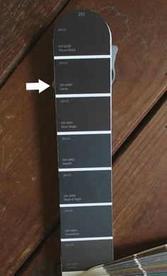 a wooden table topped with lots of different shades of gray and white paint swatches