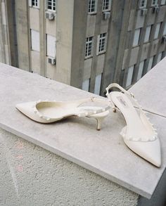 a pair of white shoes sitting on top of a cement ledge next to a tall building