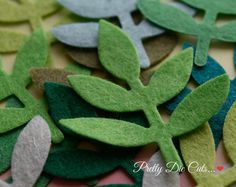 green and grey felt leaves are scattered on top of each other in this close up photo