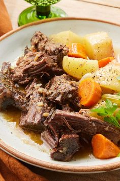 a white plate topped with meat and veggies on top of a wooden table