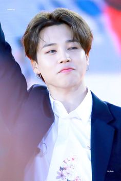 the young man is wearing a white shirt and black jacket with flowers on his lapel