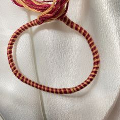 a close up of a piece of yarn on a white cloth with a red and yellow thread