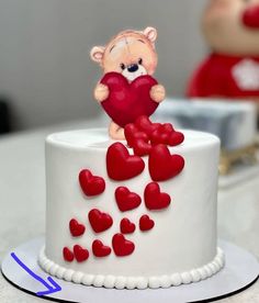 there is a small cake with hearts on the top and a teddy bear holding a heart