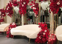 a room filled with white couches covered in red and pink flowers next to mirrors