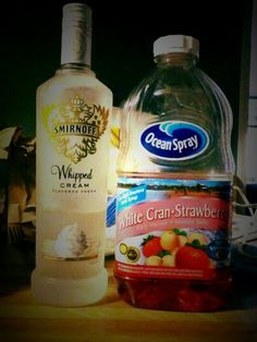 two bottles of water sitting on top of a wooden table next to a bottle of ice cream