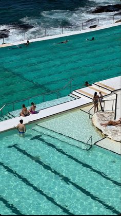 people are swimming in an empty pool near the ocean