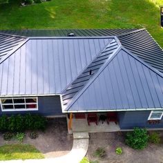 an aerial view of a blue house with a metal roof and two red chairs on the porch