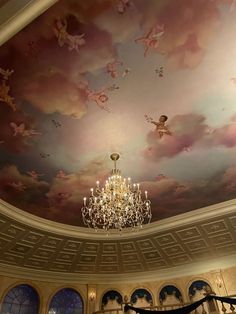 a chandelier hanging from the ceiling in front of a painted ceiling with angels