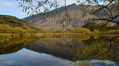 a lake surrounded by mountains with trees in the foreground