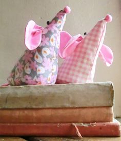 three stuffed animals are sitting on top of some books and one is wearing a pink hat