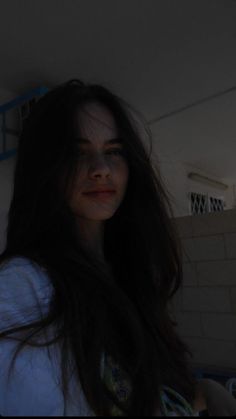 a woman with long dark hair standing in a bathroom