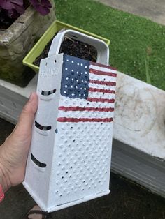 a person holding up a box with an american flag painted on the front and side