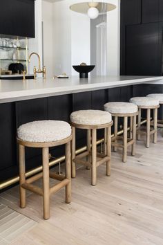 four stools are lined up in front of the kitchen counter and bar with black cabinets