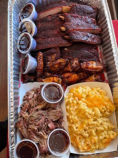 a tray filled with meat, macaroni and cheese and other food on it