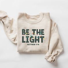 Shine Bright this Christmas with our "Be The Light" Sweatshirt! Inspired by Matthew 5:14, this cozy and inspirational sweatshirt is a beautiful reminder to let your faith shine and be a light in the world. It's perfect for spreading Christmas cheer, attending church services, or simply expressing your devotion in everyday life. Crafted from soft, comfortable materials, this unisex sweatshirt is ideal for cozy days and festive nights. It also makes a thoughtful and meaningful gift for loved ones Faith Based Gifts, Inspirational Shirts, Be The Light, Religious Christmas, Holiday Sweatshirt, Christian Christmas, Family Christmas Shirts, Inspirational Shirt, Mens Long Sleeve Tee