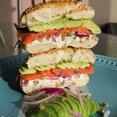 a sandwich with tomatoes, avocado and lettuce on a blue plate