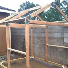 an unfinished house is being built in the back yard with wood framing around the roof and walls